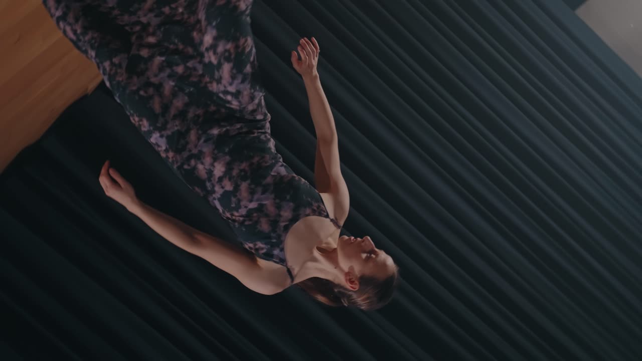 Ritratto ravvicinato di una ballerina di danza contemporanea che estende il braccio durante un'esibizione espressiva su un palco con sfondo di tenda scura.