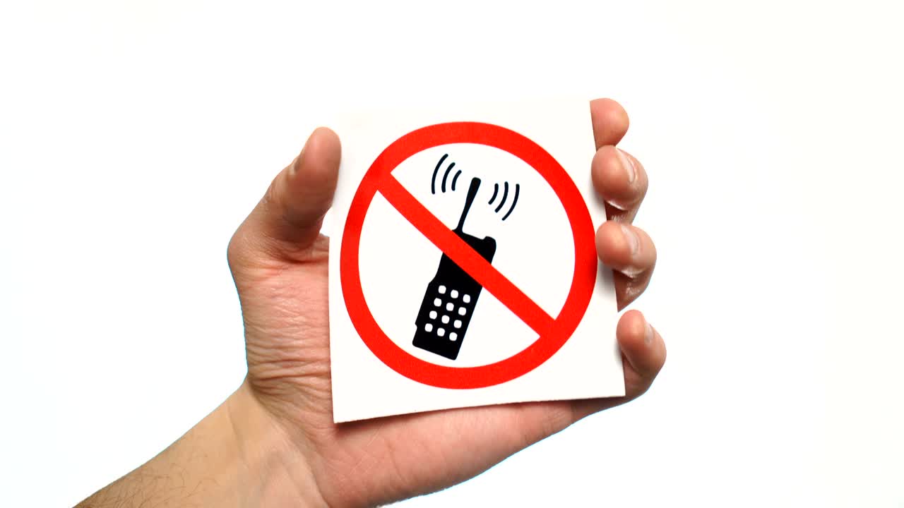 No phones allowed sign isolated. Male hand holding no phone calls sign
