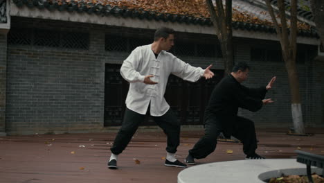 men practicing martial arts outdoors in traditional setting
