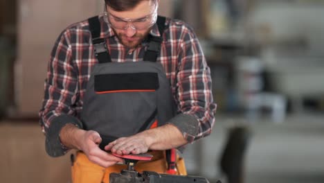 a handsome man in the form of a carpenter puts on a grinding wheel