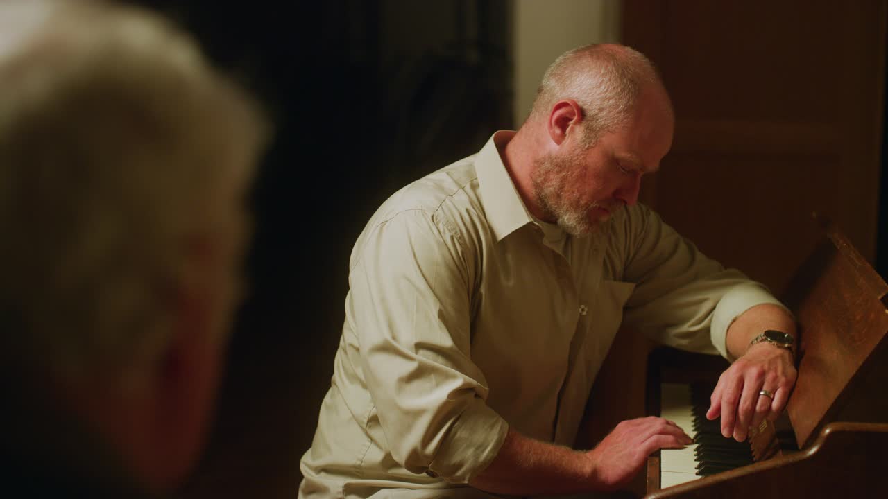 슬픈 남자가 누군가 앞에서 피아노 키를 연주합니다.