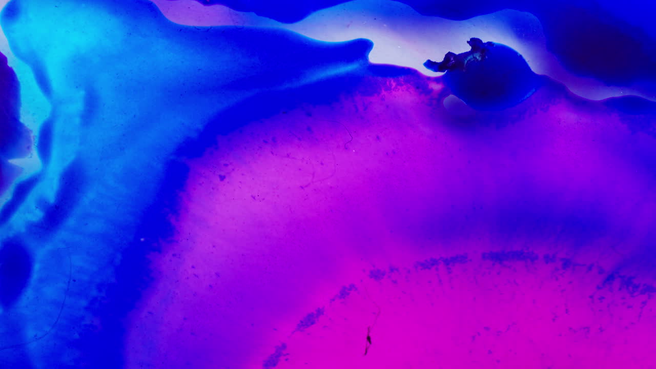 Miscela dinamica di inchiostro blu brillante con tonalità viola in un mezzo liquido. Scatto macro.