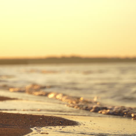 edge of sea with waves on sand shore. silhouette of the woman walking on shoreline on the water background in the evening.