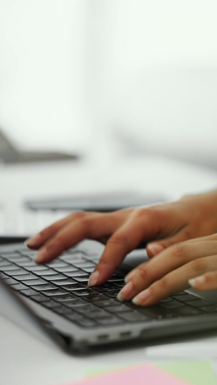 Primo piano di mani che digitano su una tastiera di laptop in un ufficio