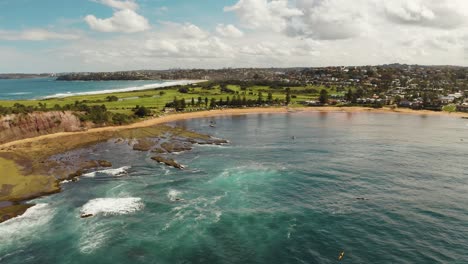 Coastal-aerial-of-Longreef-headland,-rocky-shoreline-and-sandy-beaches-in-Sydney-Australia