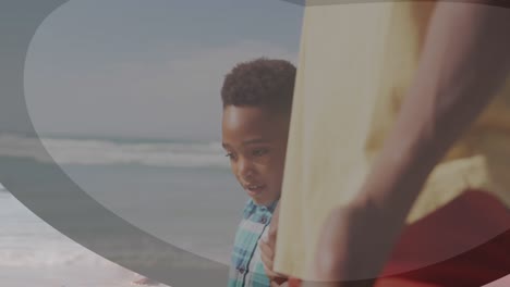 animation of shapes over african american man and his son at beach