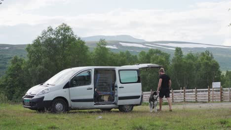 man walk towards the van with alaskan malamute