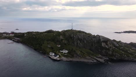 Descending-aerial-view-of-white-houses-on-small-rocky-island-in-Scandinavia