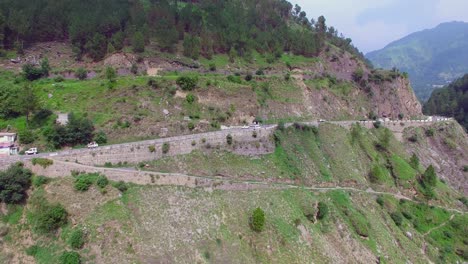 highway at the top of the mountain and a river, nepal, traffic on the road, hill with trees and forest, camera pan shot