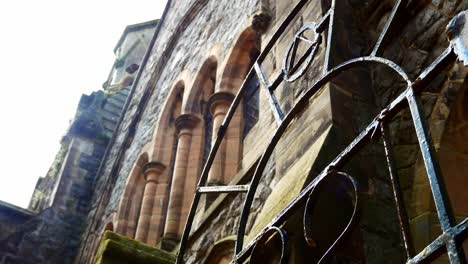 weathered freemason lodge rusted gate entrance looking up at stone wall window arches dolly left