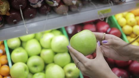 girl in supermarket taking green apples