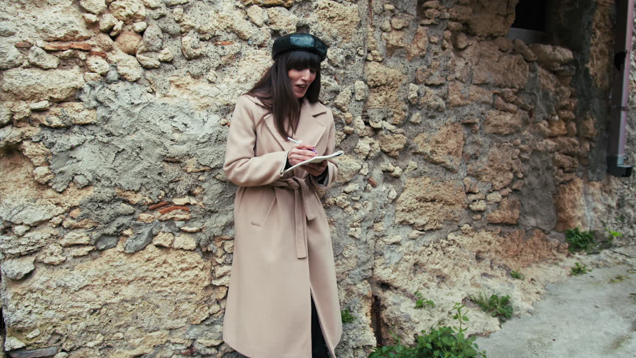 Donna che si diverte mentre scrive qualcosa sul suo taccuino per le strade del borgo.