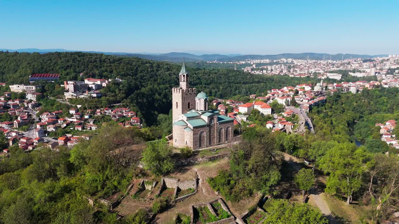 Tæt dronekredsning omkring den historiske kirke ved Tsaravets-fæstningen, der fremhæver middelalderlig bulgarsk arkitektur og stenhåndværk.