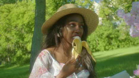 black woman calmly eating banana in park dolly in close up