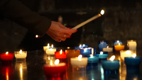 Aufnahme-Der-Hand-Einer-Jungen-Betenden-Frau,-Die-In-Einer-Katholischen-Kirche-Eine-Kerze-Anzündet