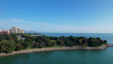 lush green park tress next to waterfront with chicago skyline drone