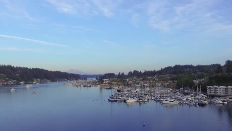 sailboats and yachts docked at the gig harbor marina and boatyard in pierce county, washington with a kayaker paddling over the calm puget sound bay - wide aerial shot