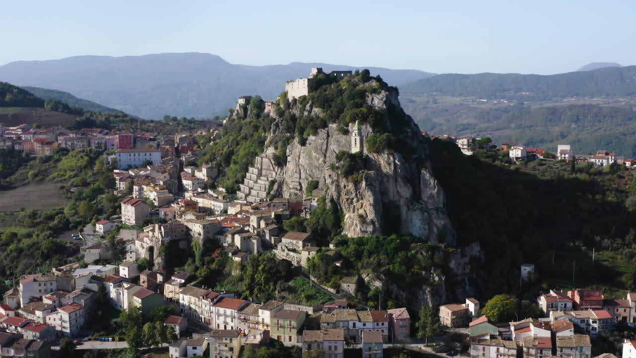 두 개의 바위 박차 사이에 산 실베스트로 교회가 있는 바뇰리 델 트리뇨 마을의 공중 선회 샷, 이탈리아의 몰리세 지역, 4k
