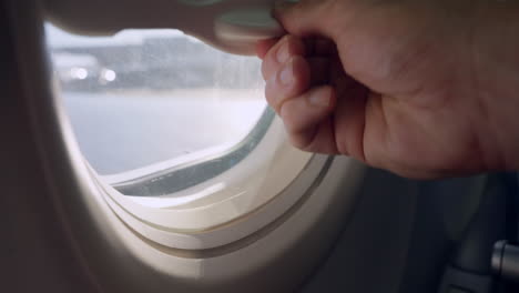 person adjusting airplane window shade
