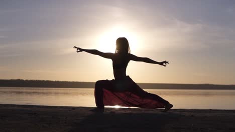 Silhouette-of-a-slender-girl-do-warrior-namaste-yoga-pose-at-sunset.-Seaside