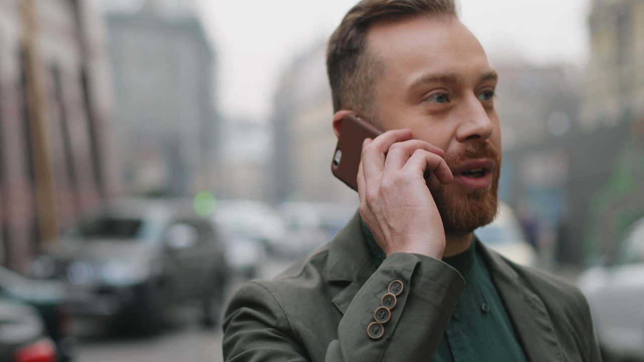 가을에 거리에서 행복하게 통화하면서 커피를 마시는 명랑한 백인 젊은 사업가의 클로즈업 보기