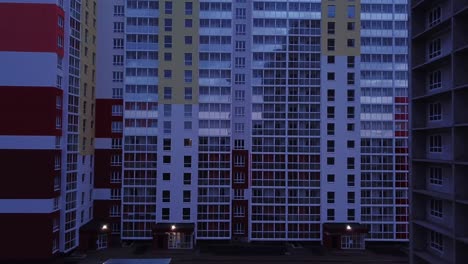 drone view of colorful facade contemporary apartment building, windows and balconies. aerial footage highrise estate at night time.