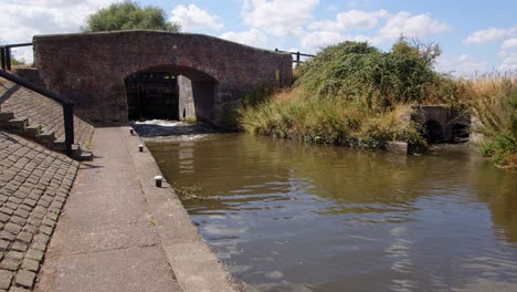 Wide-shot-off-Aston-Lock-on-the-Trent-and-Mersey-Canal-with-water-emptying-out-of-the-canal-through-sluice-gates