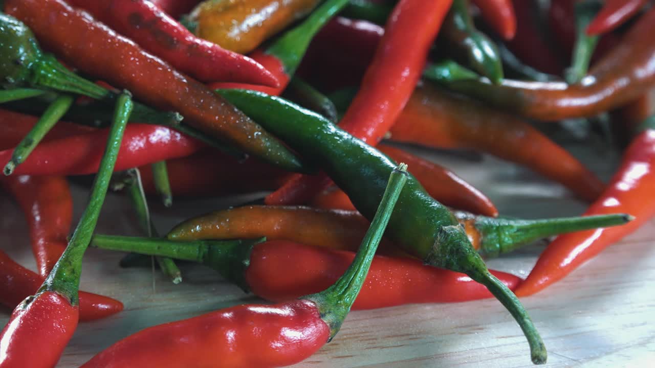Green and Red Chillies Spinning on Wooden Board