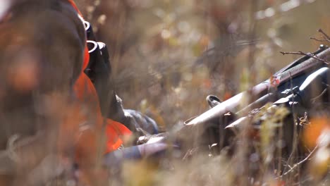 hunter waits by rifle in tall grass