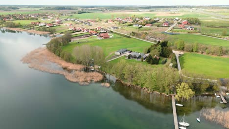 A-green-shore-of-a-large-lake,-with-a-small-picturesque-village-on-it