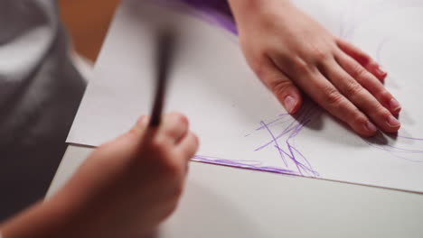 little girl paints paper with purple pencil drawing sketch