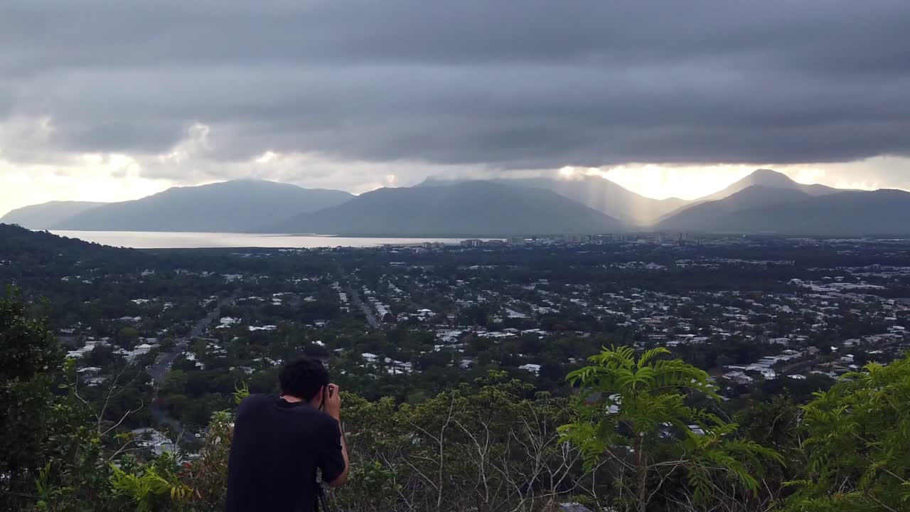 사진작가 는 해 가 입구 를 가로질러 멀리 있는 산 에서 뜨고 있는 사진 을 찍고 있다