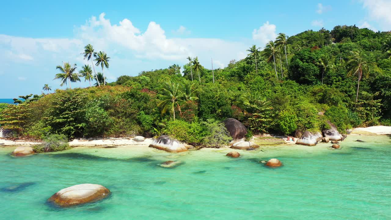 Costa tranquila de una isla tropical con acantilados de piedra caliza bañados por aguas claras y calmas de una laguna turquesa y un bosque de palmeras en Tailandia