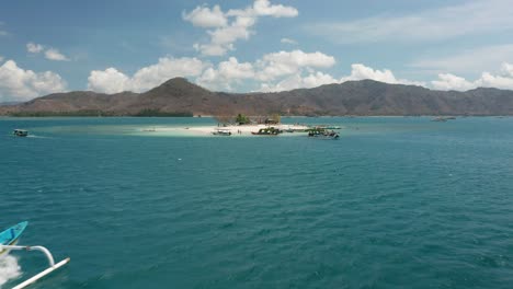 traditional boat travels to gili kedis with lombok mountains in background