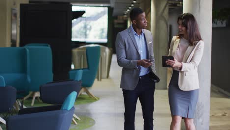 diverse businessman and businesswoman discussing and using tablet in modern office