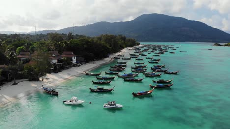 long tailed traditional thai boats anchored by a sand beach on tropical island