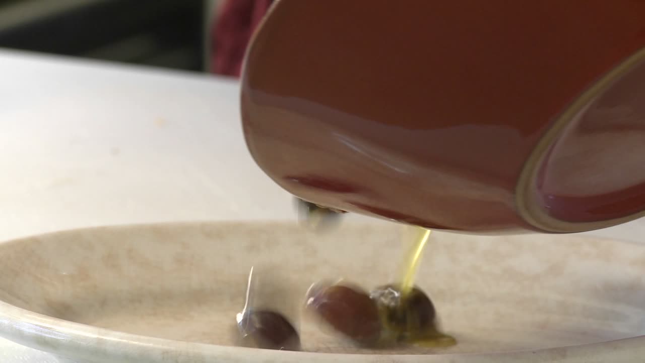 Pouring olives from a bowl into a plate