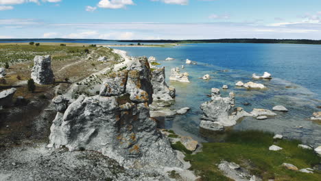 Aerial-view-of-huge-rock-outcrops-at-empty-sea-coast,-arc-shot