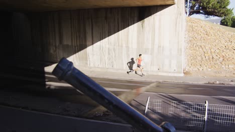 fit afrikanischer amerikanischer mann trainiert in der stadt, läuft unter einer brücke