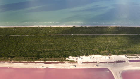 coche conduciendo en la carretera del istmo entre el mar y los estanques de sal rosa en méxico