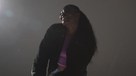 retrato de estudio de una mujer joven bailando con iluminación baja contra un fondo gris 13