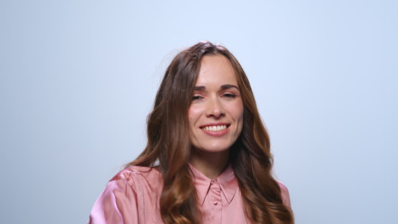 Imprenditrice che fa il gesto del sì in studio. Donna che sorride su sfondo blu.