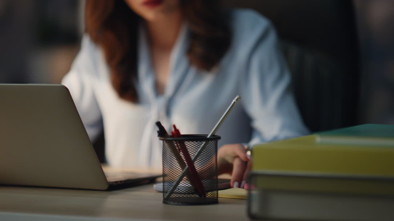 Donna distratta da un messaggio sullo smartphone in primo piano nell'ufficio di sera. Signora che legge un'email.