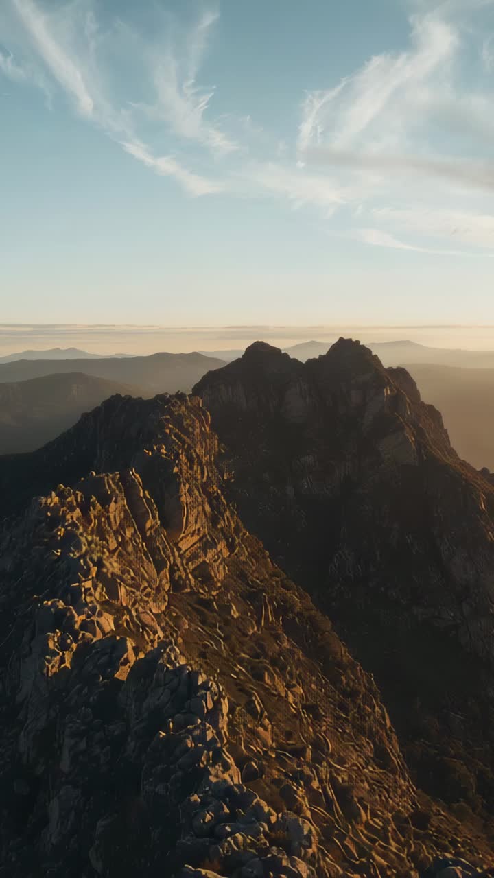 Video verticale: telecamera in movimento che rivela una cresta frastagliata illuminata dalla luce dorata, che mostra la profondità e le cime gemelle