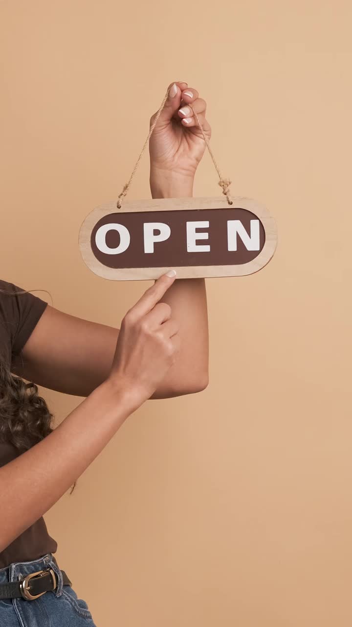 Woman pointing to the open sign of an space. Vertical Footage