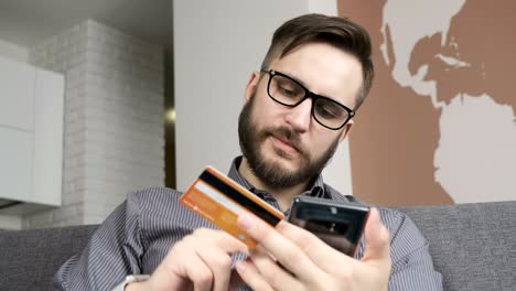 man using online banking with smart phone and card