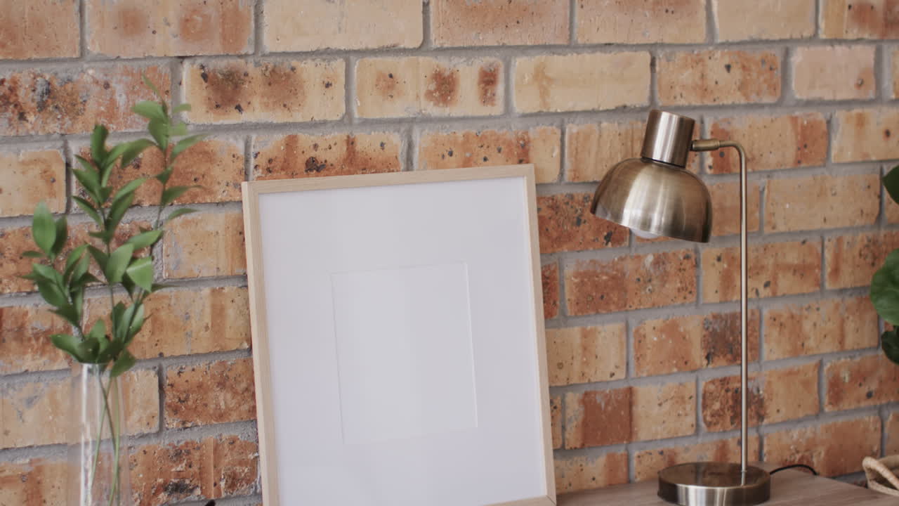 marco de madera y planta en el escritorio con espacio de copia contra la pared de ladrillo