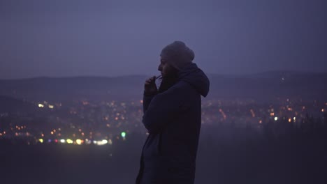 Girl smoking electronic cigarette outside, blurry town lights in background, middle side shot with copy space