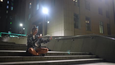 mujer tomando selfies en las escaleras de la ciudad por la noche