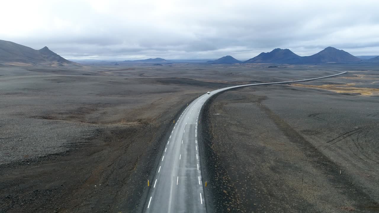 Car passing by a road in the middle of a volcano desert